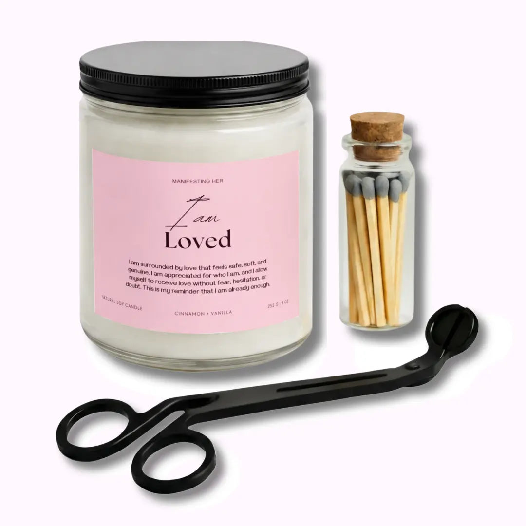 Candle labeled 'I am Loved' with a jar of matches and a pair of scissors on a white background
